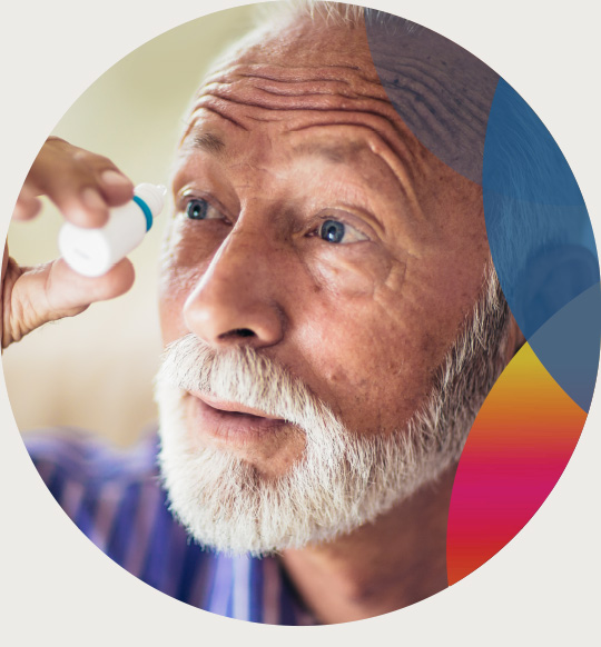 An older man puts eye drops into his left eye.