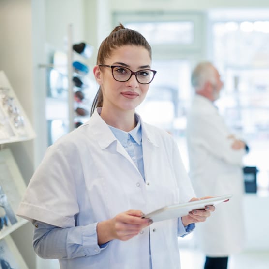 A female optometrist standing in an optometrist's office with a tablet in her hand.