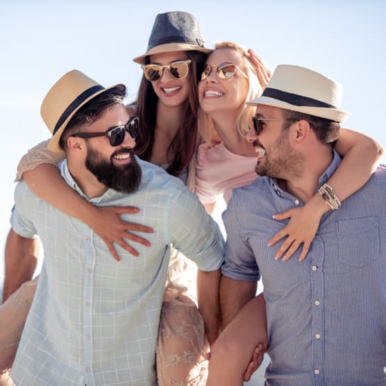 Two couples standing together outside, and they're all wearing sunglasses.