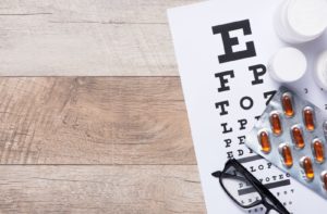 A Snellen chart, an eye glasses and vitamins good for the eyes on a table