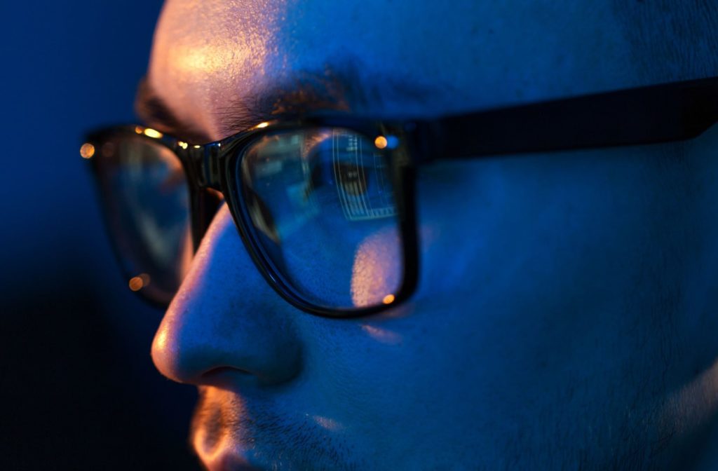 A man wearing blue light protective glasses so he doesn't get eye strain from the computer screen.