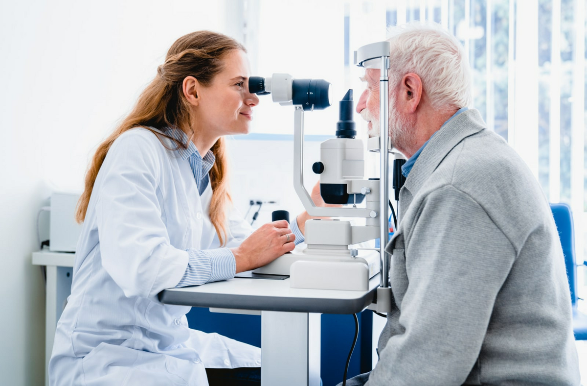A female optometrist examining an older mans eyes.