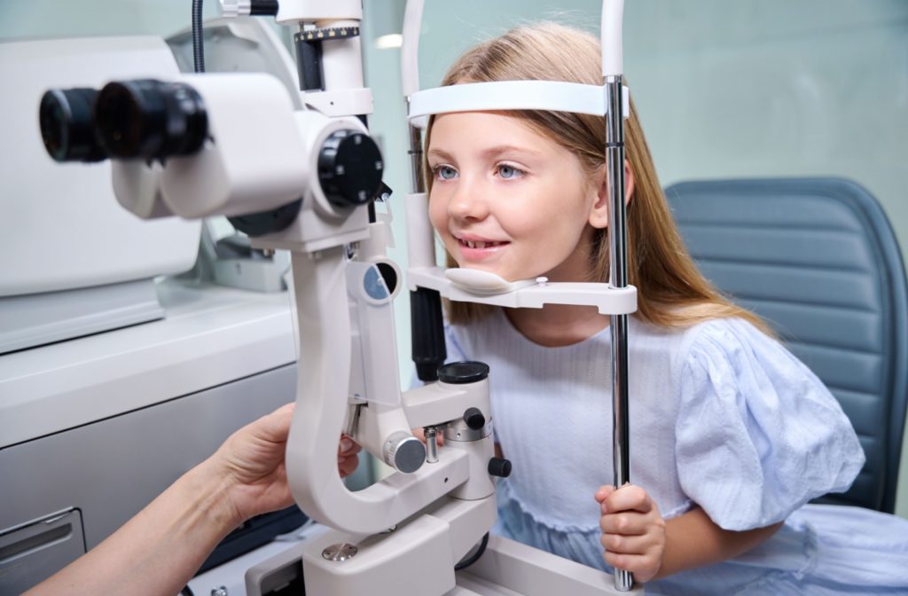 A child smiling during an eye exam with her optometrist.