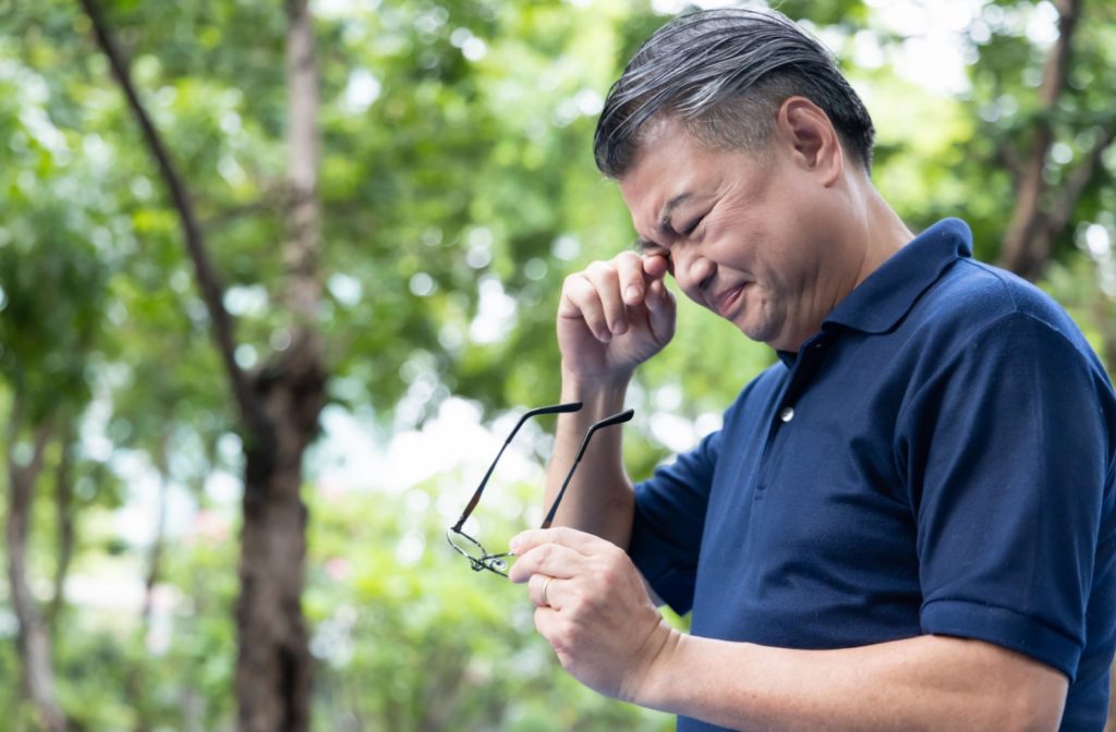 A man with a family history of glaucoma rubbing his eyes due to discomfort.