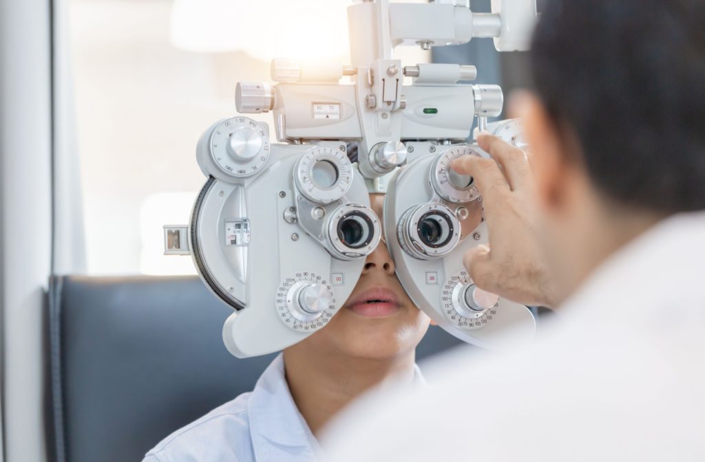 An optometrist performs a refraction test on a child during a routine eye exam.