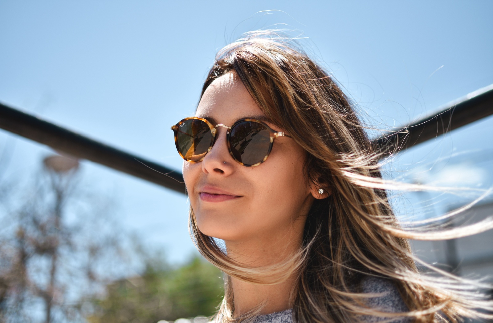 A person wearing stylish sunglasses comfortably waits outside on a sunny day
