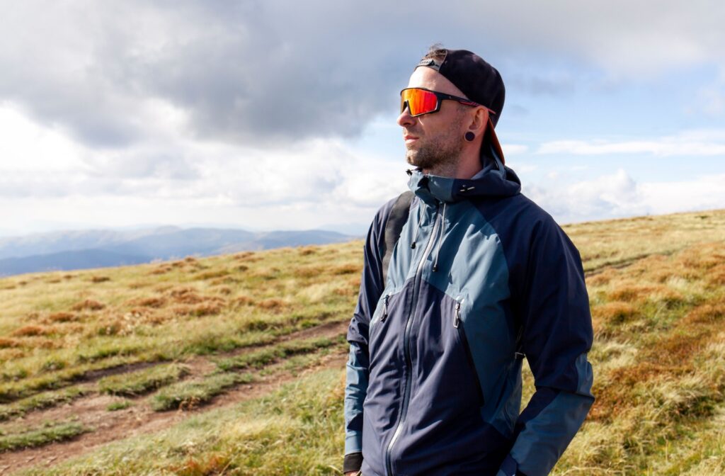 An active hiker wearing polarized sunglasses looks into the bright horizon.