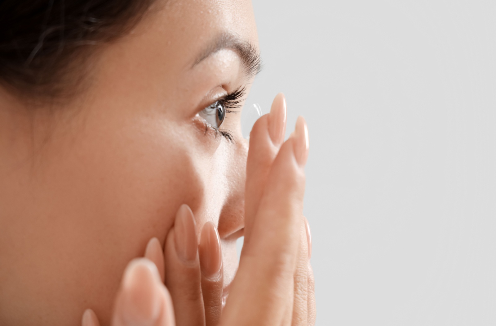 Close-up of a woman inserting a contact lens into her eye, demonstrating vision correction for astigmatism.