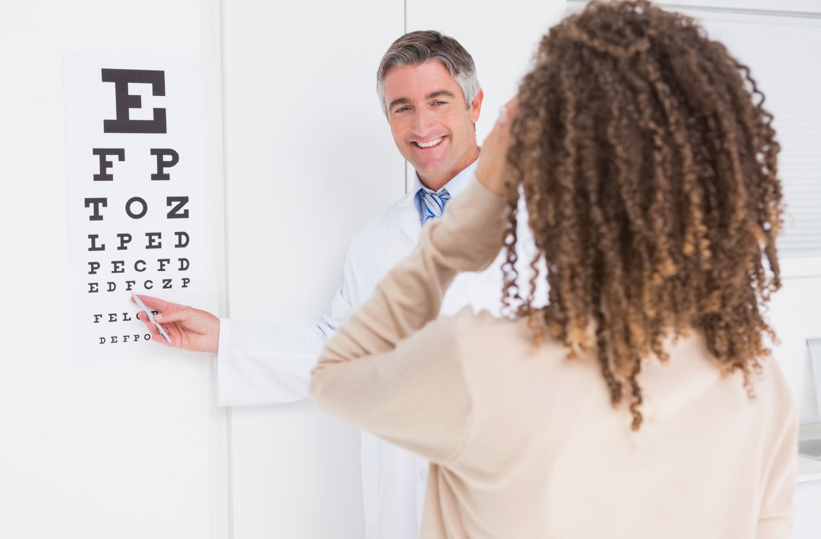 An eye doctor gets their patient to read a Snellen eye chart to test visual acuity.