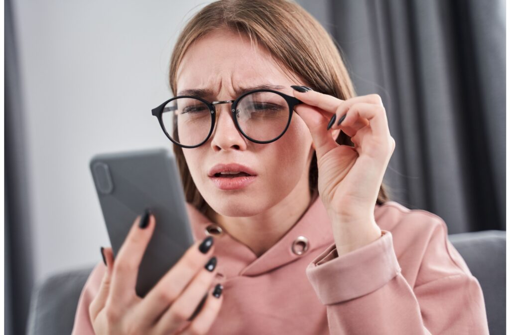 An adult squints while looking at their phone, even though they're wearing glasses.