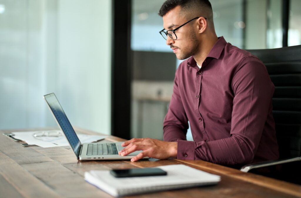 A person wearing glasses and looking at a computer screen for work